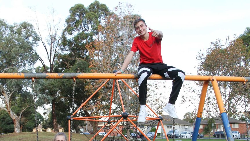 Two youths hang off a playground swing set