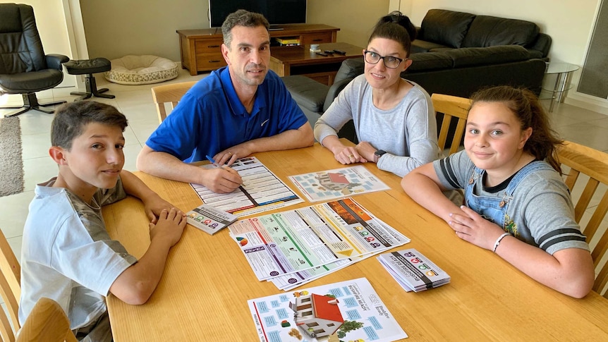 Liza and Frank Marando sit at a table with their two children, with bushfire preparation brochures spread before them.