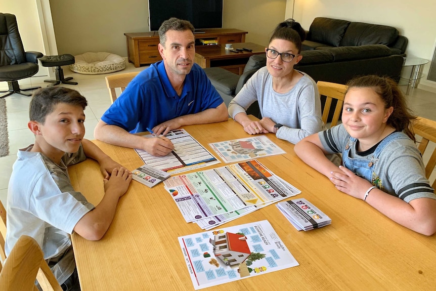 Liza and Frank Marando sit at a table with their two children, with bushfire preparation brochures spread before them.