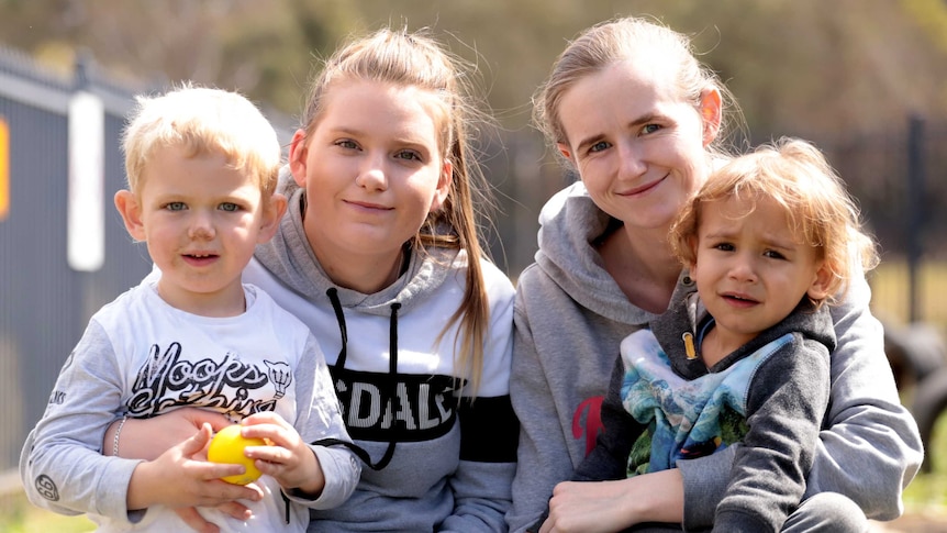 Two mothers sit with their young sons