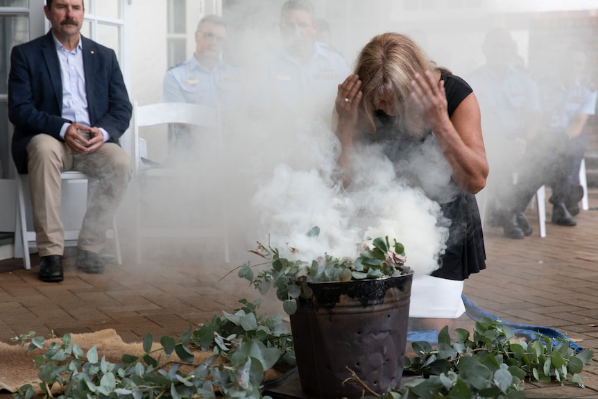 A woman bends over to immerse her face in smoke