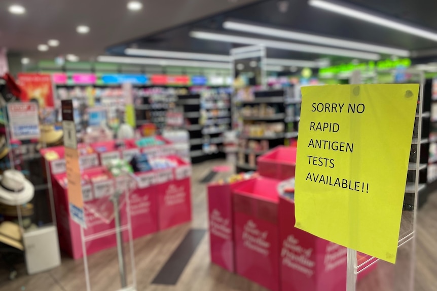 There is a pale yellow sign at the entrance to a chemist "sorry no quick antigen tests available !!"