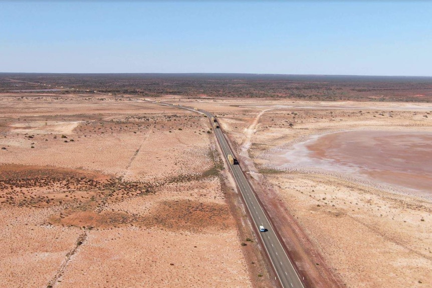 An aerial shot of drought-stricken land in Meekatharra, with trucks driving on the highway.