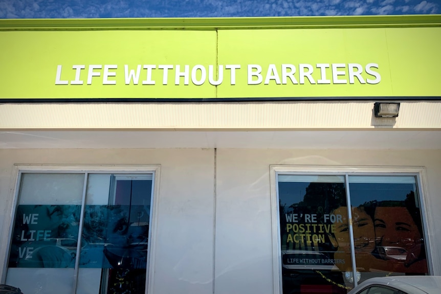 The exterior of a Life Without Barriers office building. In one of the windows is a sign that says "We're for positive action".