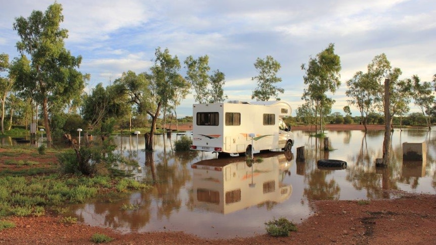 A caravan in a puddle of water at the flooded Curtin Springs campground in the NT