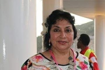 Woman in white and black floral dress smiles at camera.