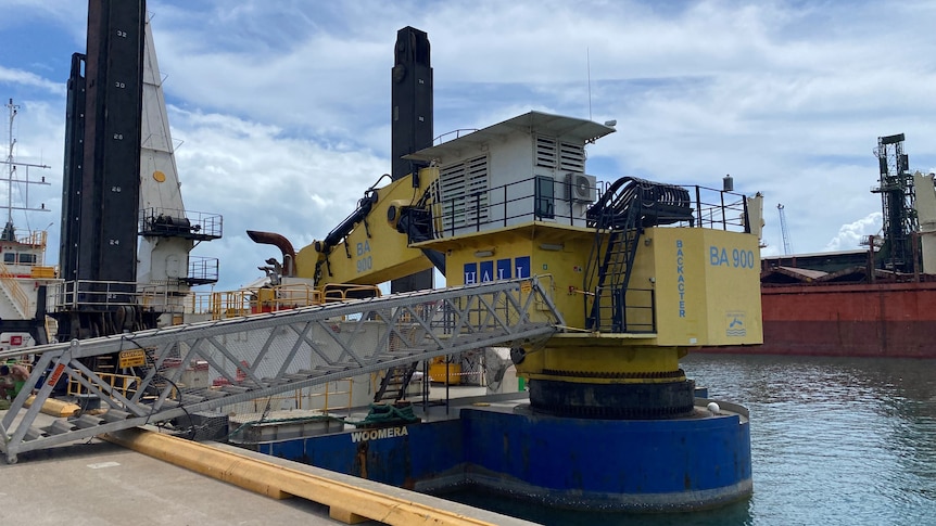 The end of a dock in a port with a dredger moored.