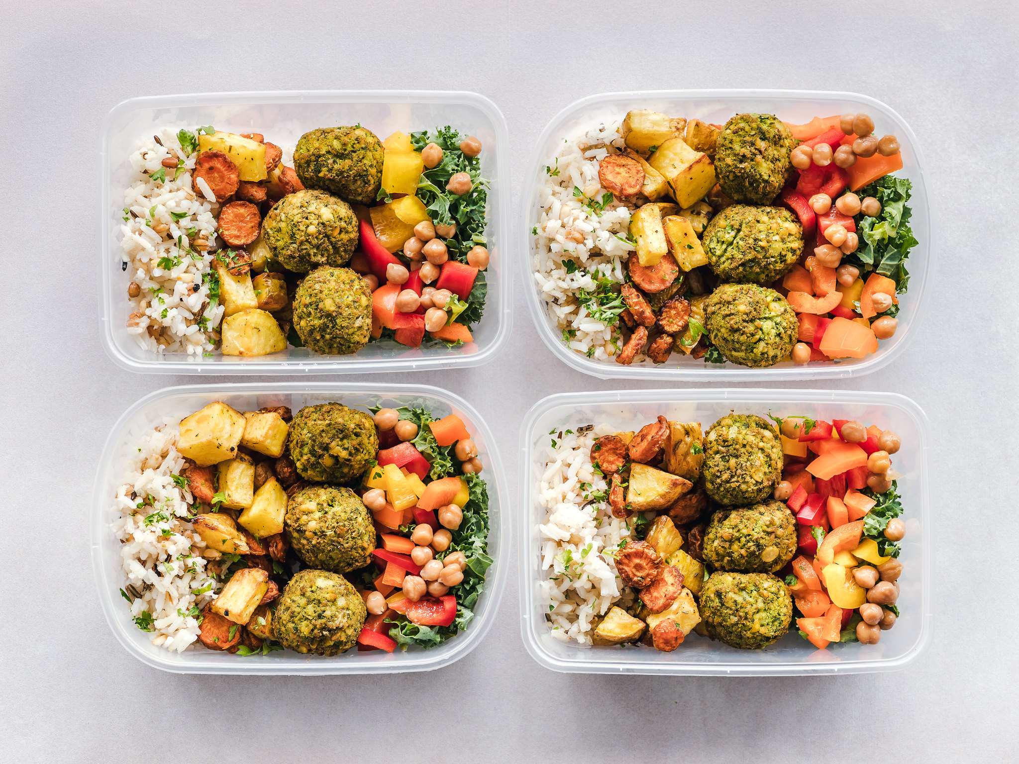 Four containers filled with healthy looking food.