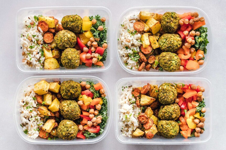 Four containers filled with healthy looking food.