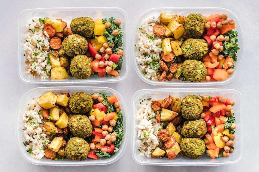 Four containers filled with healthy looking food.