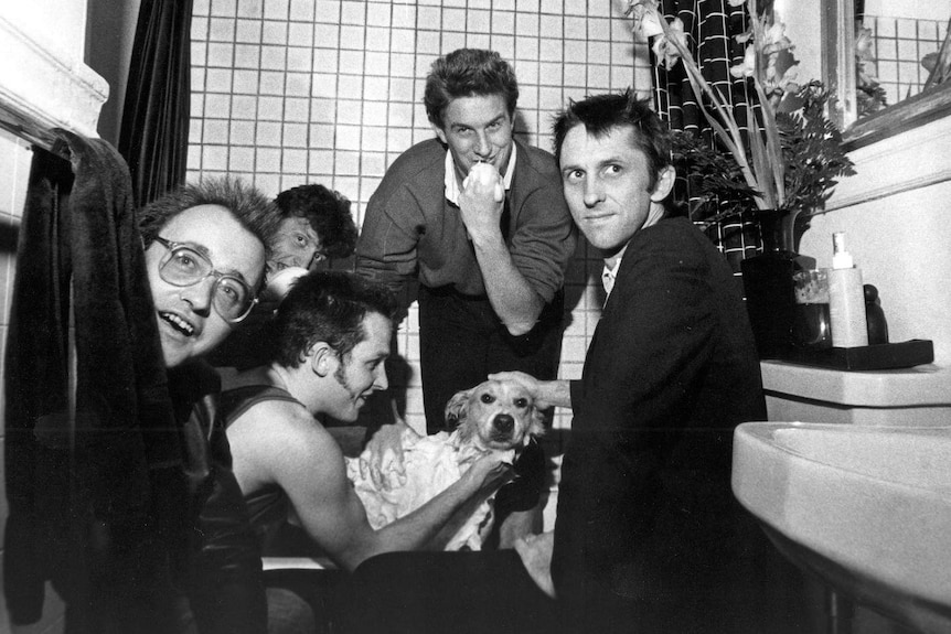 Members of Mental Anything in a bathtub patting a dog