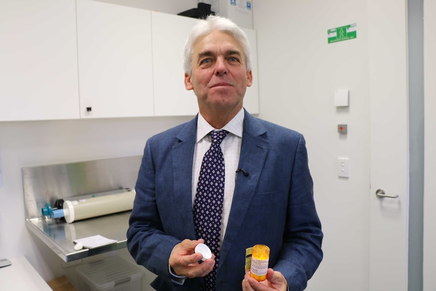Professor Peter Gibson holds a bottle of the antibiotic azithromycin.