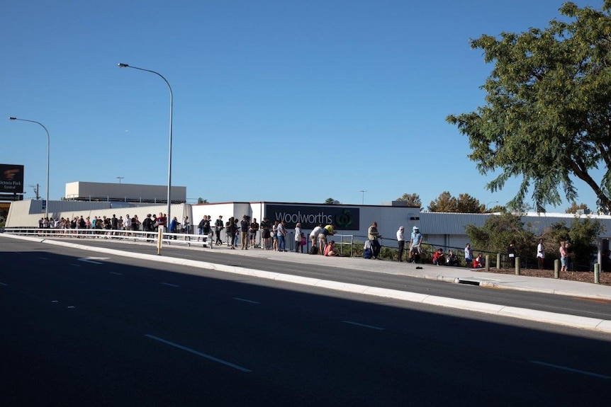 Long line of people queue outside Centrelink in Victoria Park, seen from across the street