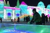 A man plays ping pong on an ice table, with a colourful structure built from ice in the background.