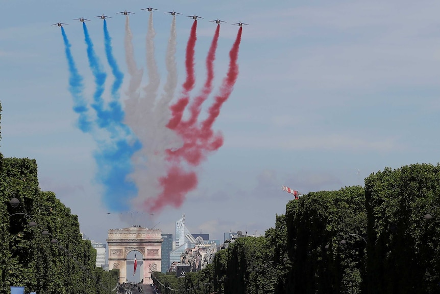 French Alphajets fly over the Champs Elysees avenue, leaving trails of blue, white and red smoke during a Bastille Day parade.