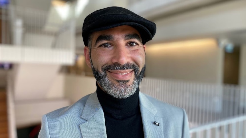 Akrim Mahouachi smiles at the camera wearing a beret.