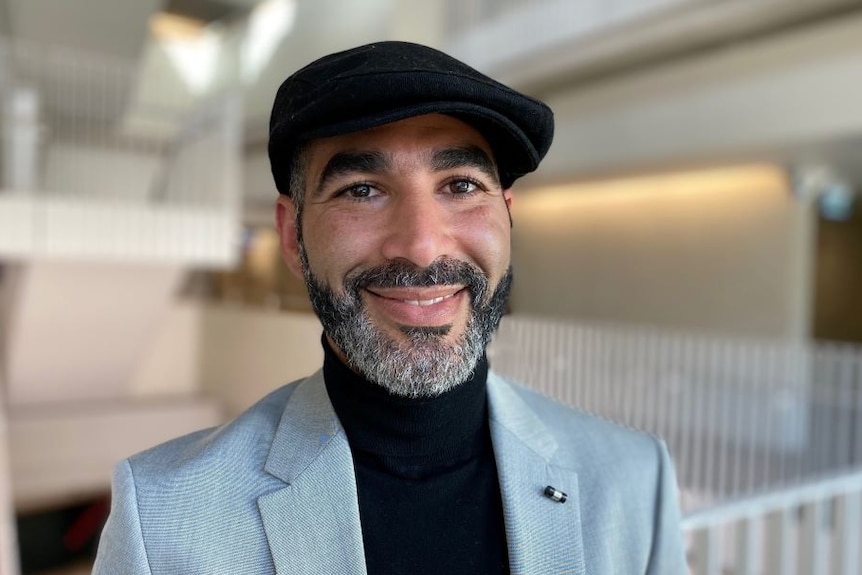 Akrim Mahouachi smiles at the camera wearing a beret.