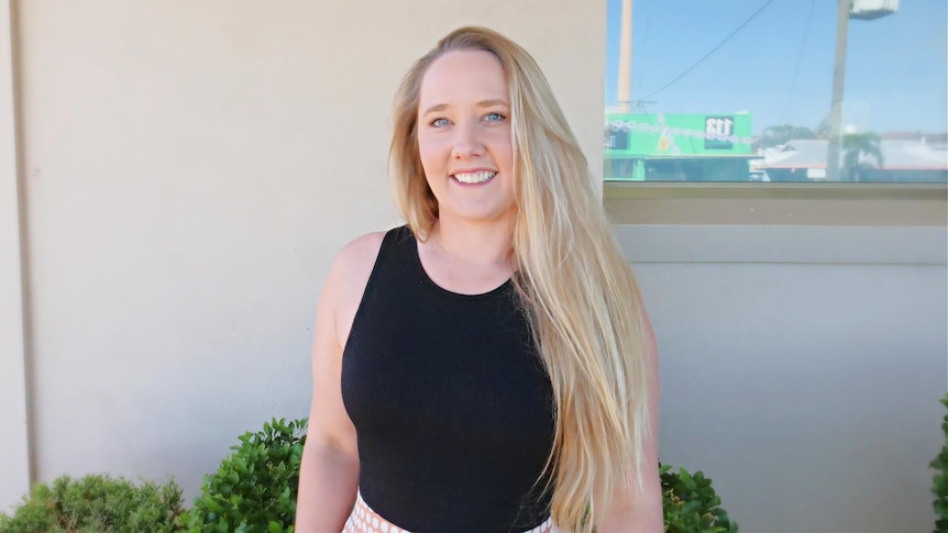 Woman with long blonde hair wearing black shirt smiles at camera