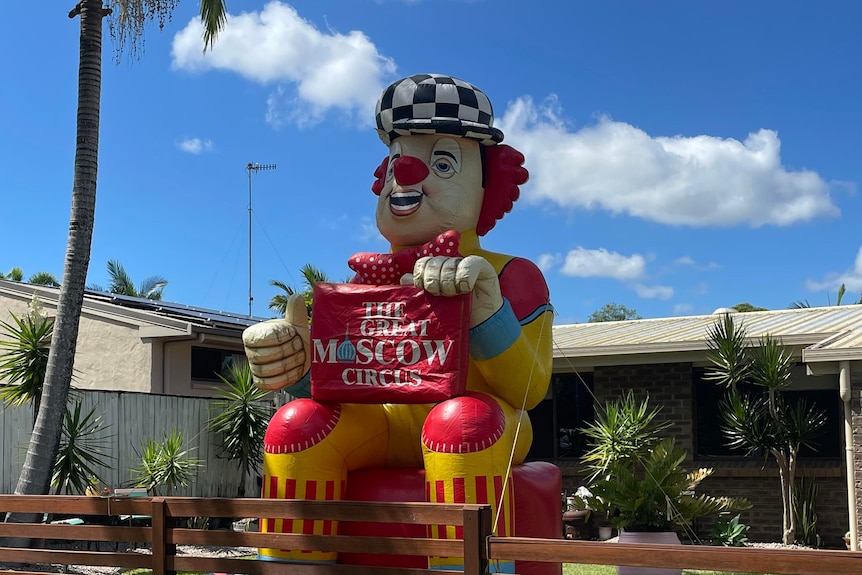 inflatable clown behind a fence in front of a house 