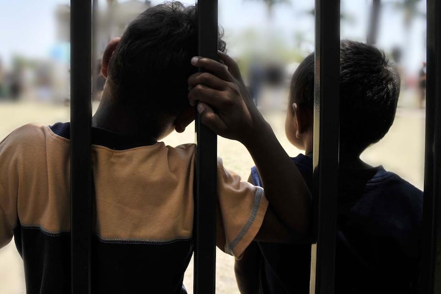 Two Aboriginal children lean on a fence (AAP: Tony Phillips)