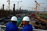 Workers survey the construction site of the terminal for the Beijing New Airport