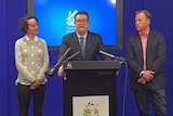 Matthew Groom stands at a podium flanked by his wife, Ruth and Tasmanian Premier Will Hodgman.