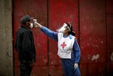 A Red Cross volunteer measures the temperature of man inside the Fraga slum in Buenos Aires.