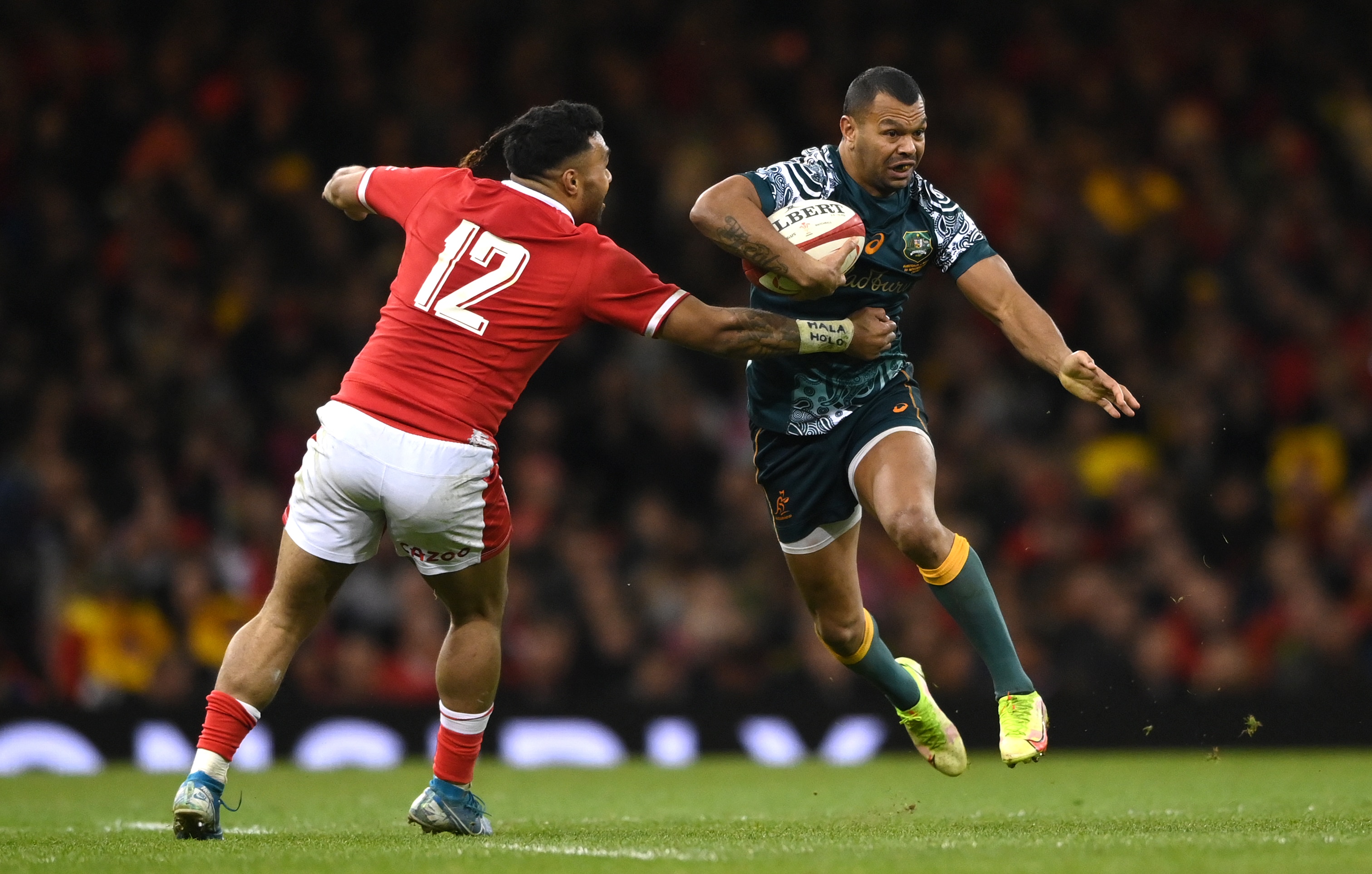 Wallabies player Kurtley Beale tries to twist his body as he runs to evade a Welsh tackle.