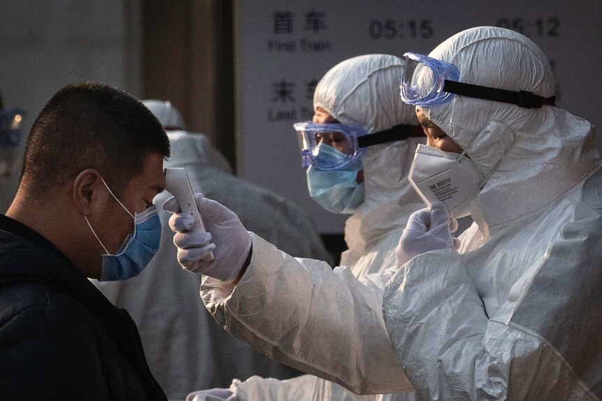 A Chinese health worker checks the temperature of a woman