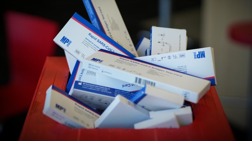 Expired rapid antigen tests (RATs) fill a red office bin marked landfill