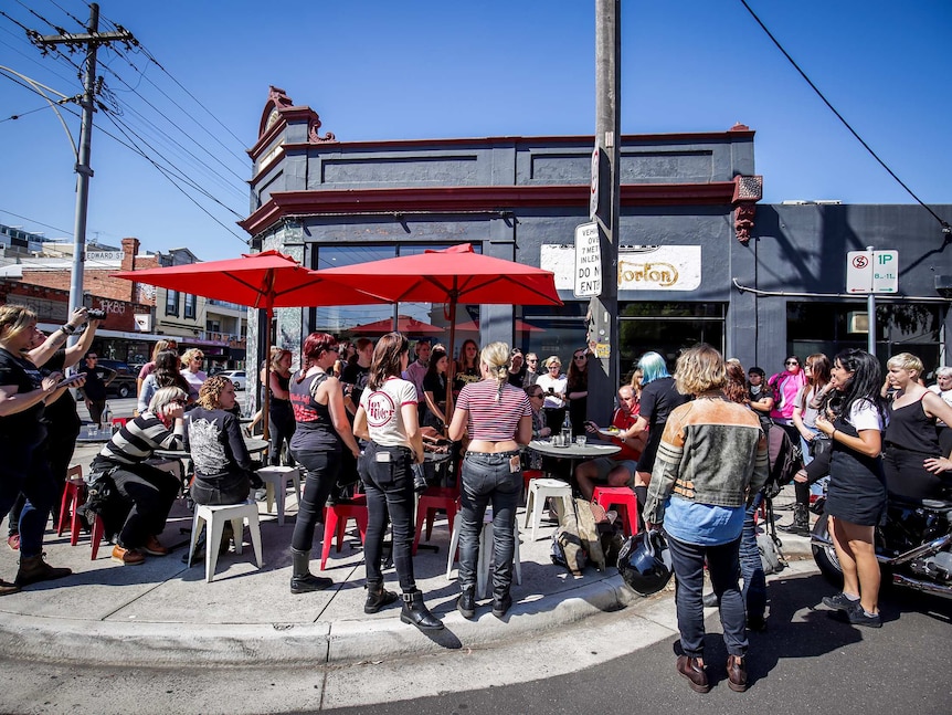 A crowd of women outside a cafe with red umbrellas