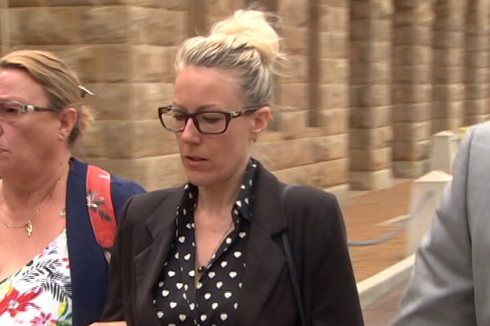 A woman in a black jacket and white spotted top walks outside court with an older woman in a white flowery top.