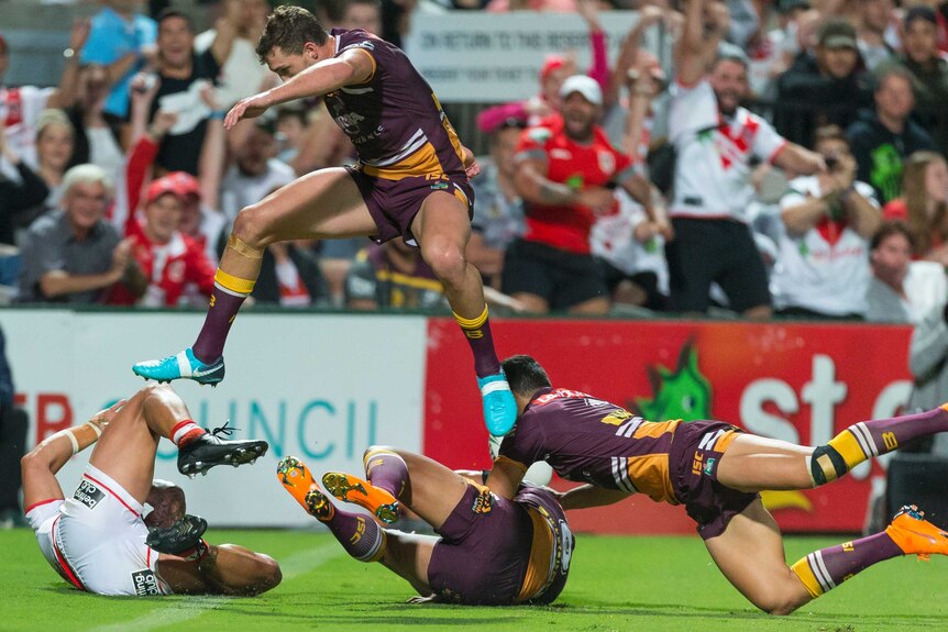 Tyson Frizell scores a try for the Dragons as Corey Oates hurdles a Broncos teammate.