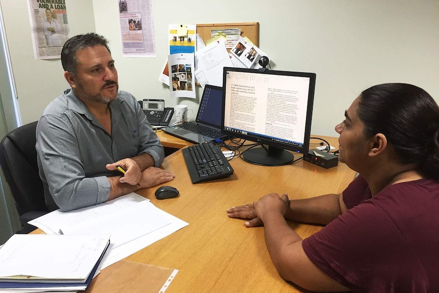 Jon O'Mally sits with client Rhonda Brim at a desk in an office in Cairns.
