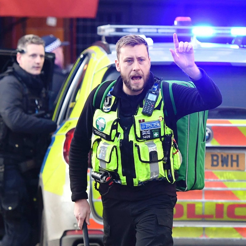 A London police officer standing in front of a patrol car.