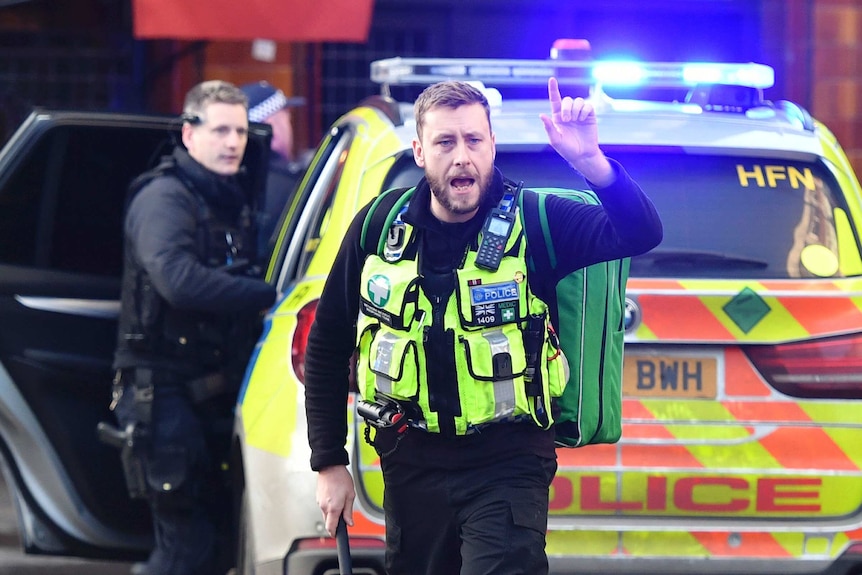 A London police officer standing in front of a patrol car.