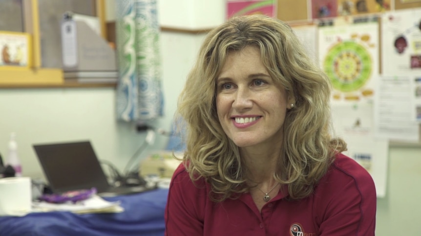 A female clinical researcher smiles while inside an ear clinic