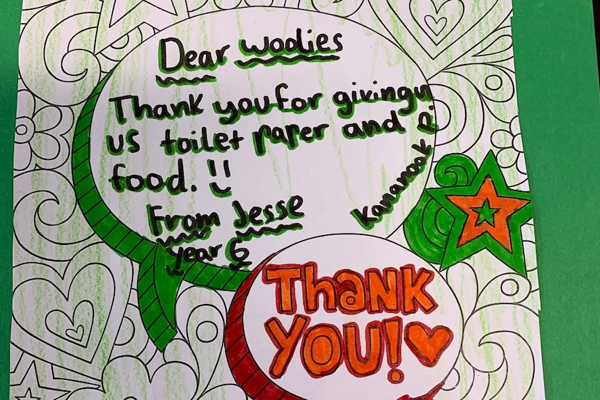 A green card with printed stars, flower and hearts written on by a child thanking Woolies staff.