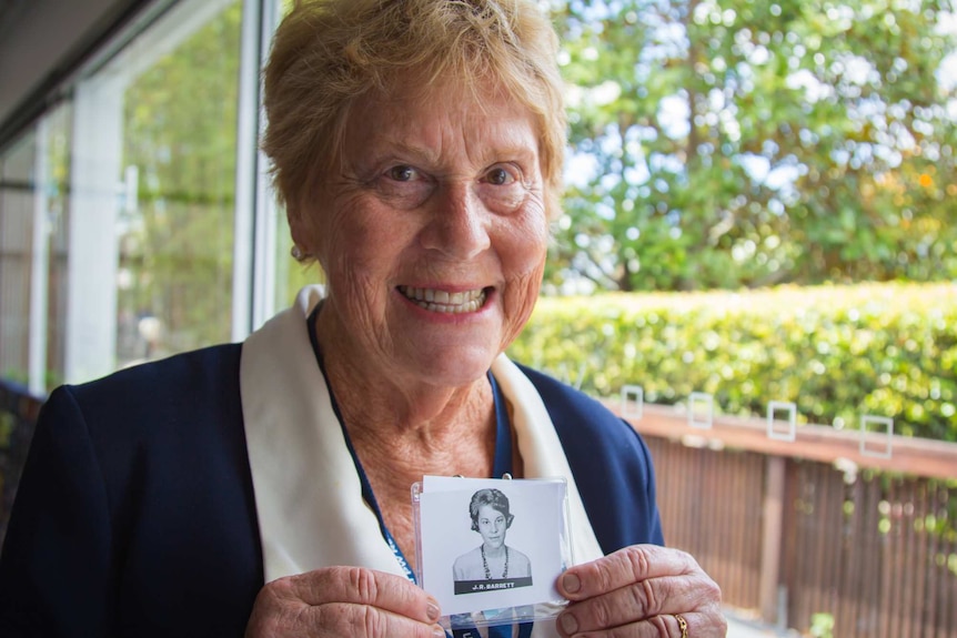 Lady holding a black and white mugshot.