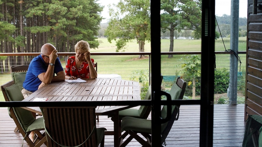 A man and a woman sit at an outdoor table on a deck doing a crossword together for a story on share housing when retired.