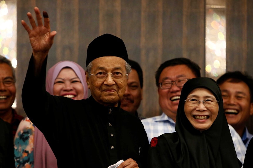 Mahathir Mohamad saluda mientras está rodeado de gente.
