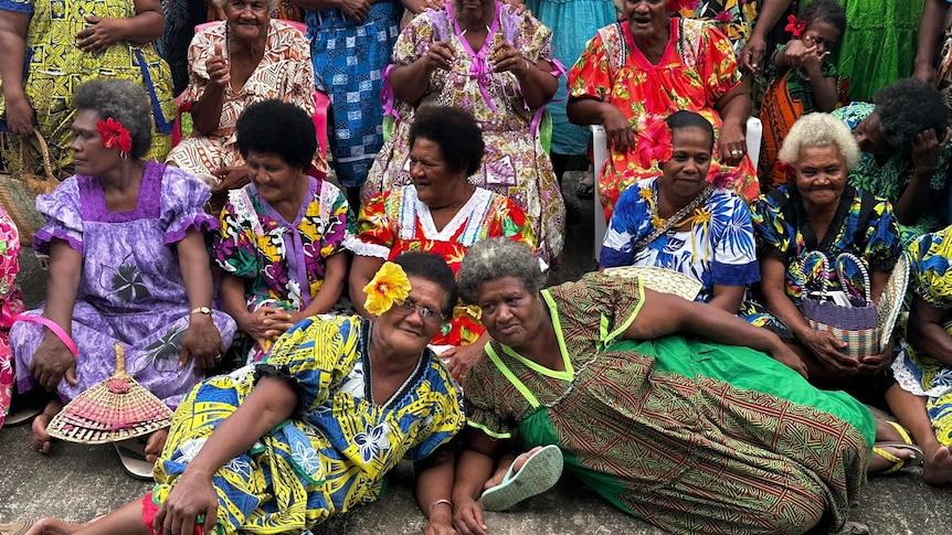 Women of Vanuatu wear bright dresses, smiling at the camera.