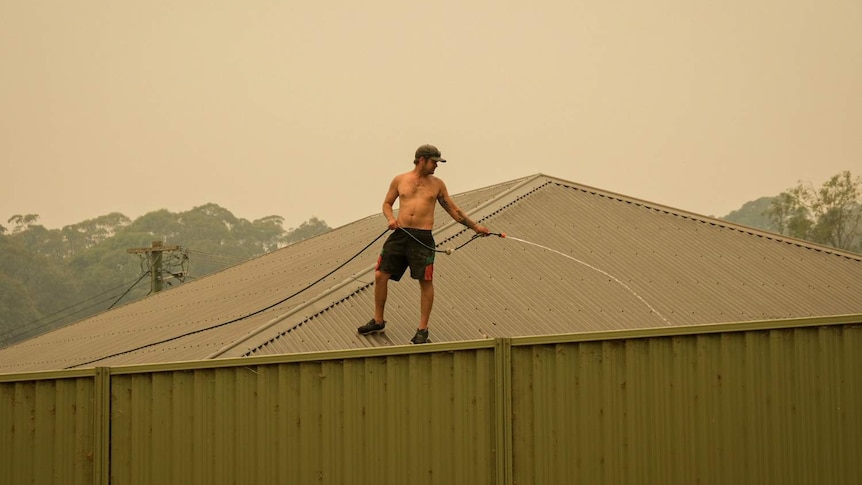 A man with a hose on top of his house