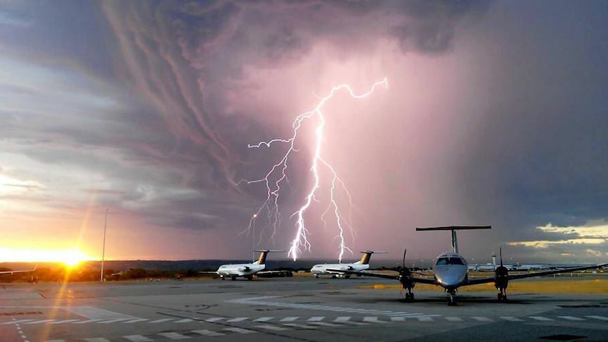 Lightning strike above two planes on the tarmac.