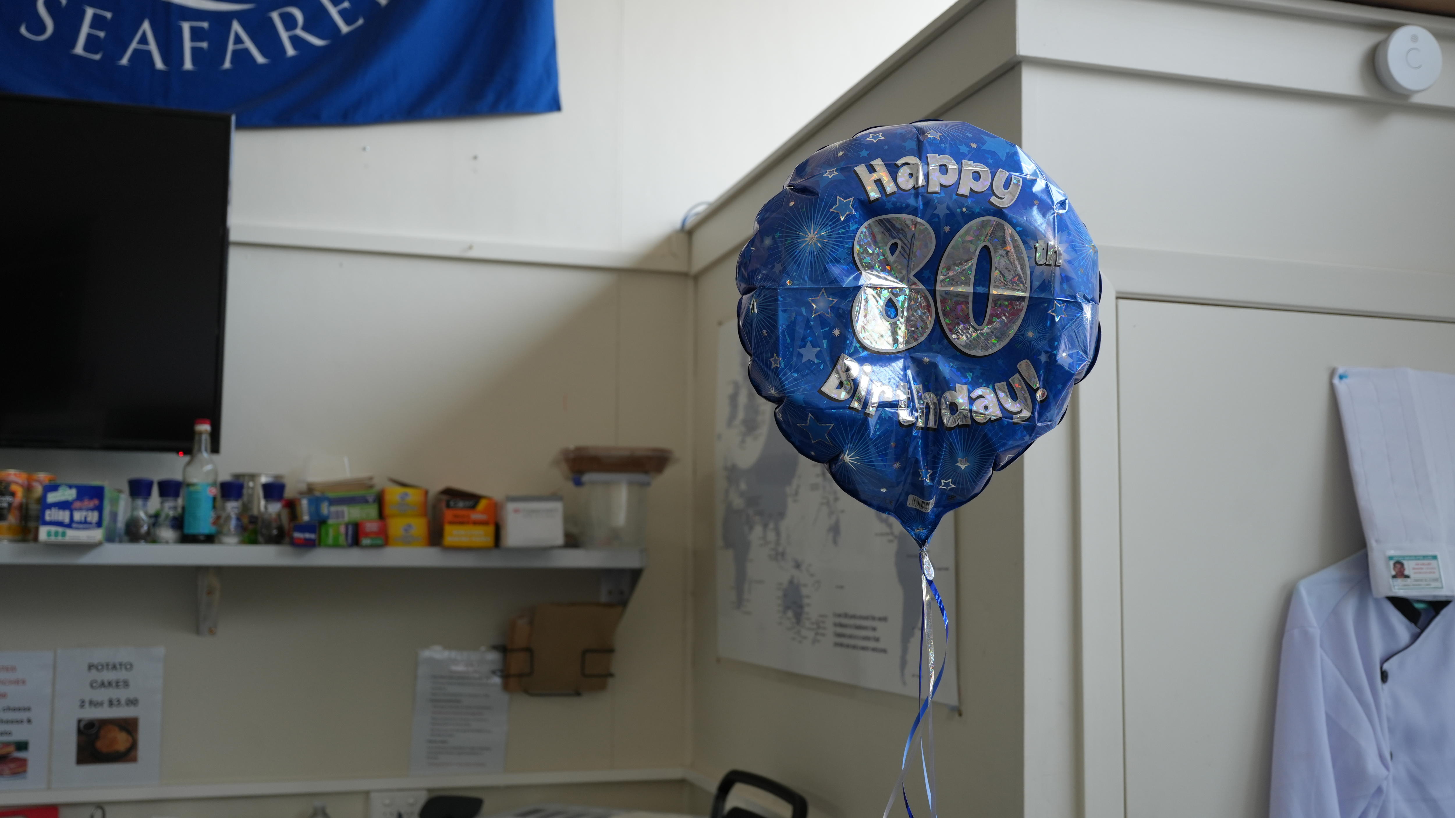 A blue birthday balloon that reads "Happy 80th Birthday"..