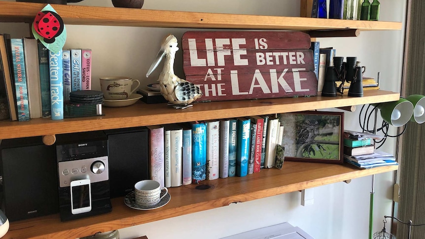 A set of shelves with books and a sign that says 'life is better at the lake'