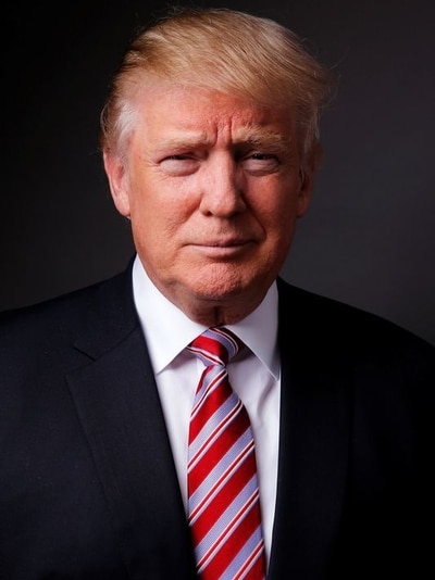 Man wearing suit and red and blue tie poses for a portrait