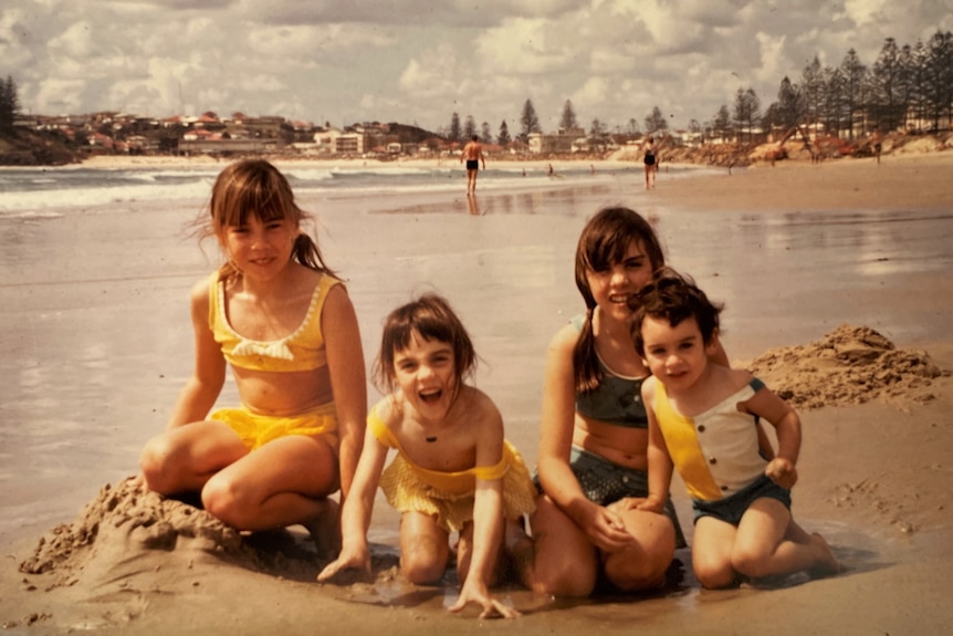 1970s photo four girls sit on the beach playing in the sand 