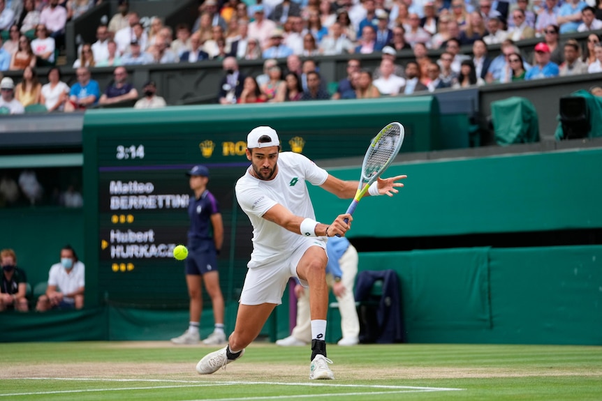 Matteo Berrettini gets almost down on one knee to play a backhand return at Wimbledon.