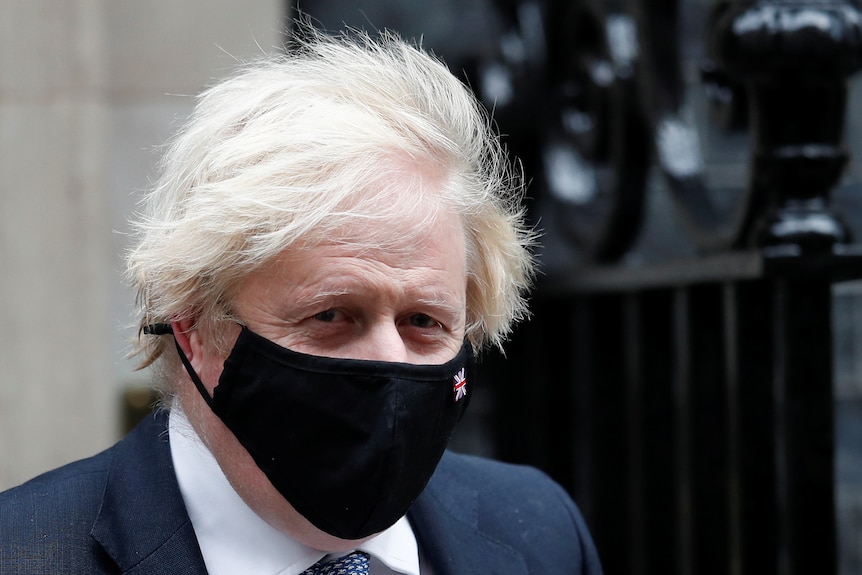 Boris Johnson wears a black face mask outside of Downing Street
